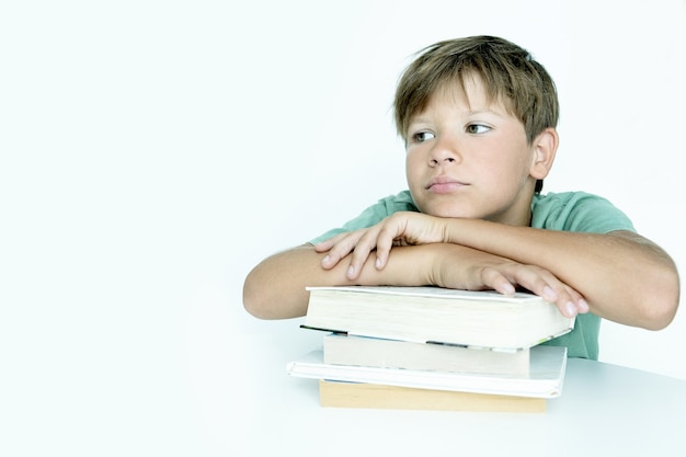 El muchacho triste con el libro hace la tarea escolar. De vuelta a la escuela. Colegial infeliz con libros de texto. La educación a distancia.