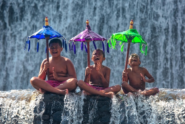 Los muchachos alegres felices se divierten en la cascada en Bali en Indonesia