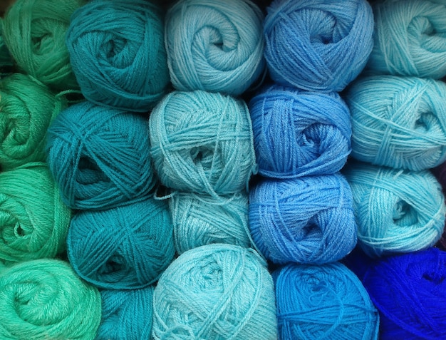 Foto muchas bolas de hilo de lana en tonos naturales de verde y azul para tejer, crochet. fondo texturizado