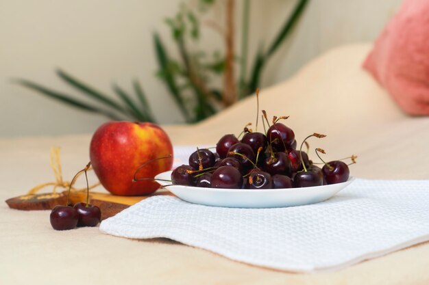 Foto muchas cerezas brillantes y jugosas se encuentran en un plato blanco al lado del libro.