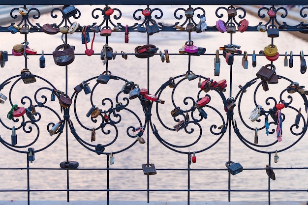 Foto muchas cerraduras diferentes colgando de la valla. la cerradura cerrada en el puente - tradición de la boda.