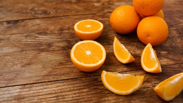 Muchas deliciosas naranjas maduras en la mesa de madera Frutas enteras y en rodajas