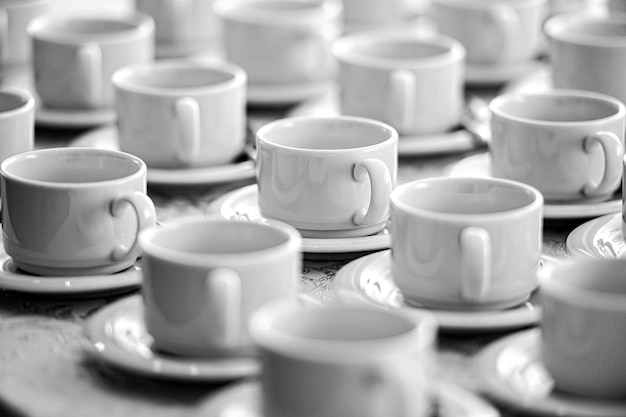 Muchas filas de tazas blancas puras con platos para tomar café o té