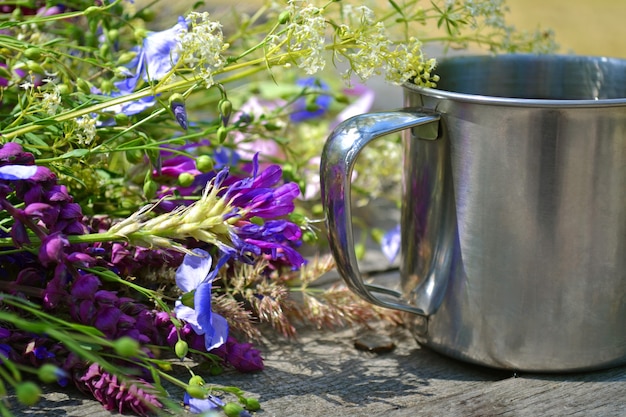 Muchas flores con taza de hierro de campamento para el turismo.