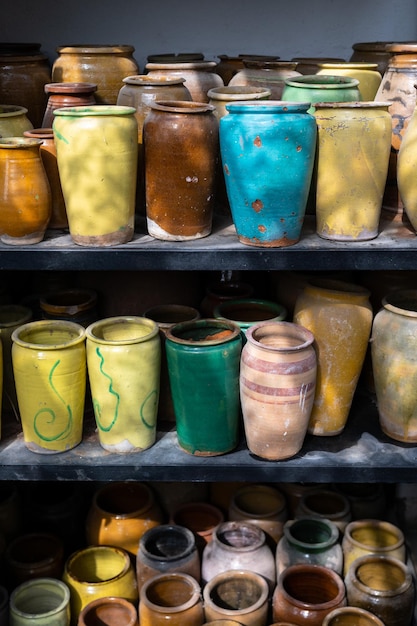 Muchas jarras de arcilla coloridas hechas a mano y jarrones únicos de varias formas en estantes en el mercado local