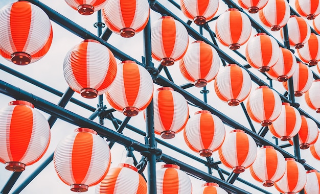 Muchas linternas de papel orientales rojo-blanco de papel colgando en una fila en el cielo azul