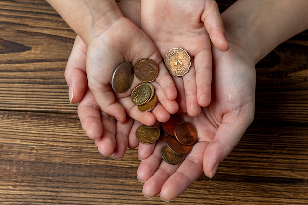 Muchas manos sosteniendo monedas en las palmas. Compartir, caridad, concepto de familia.