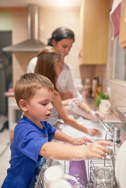 Muchas manos en el trabajo Foto de un niño lavando platos con su familia en el fregadero de la cocina