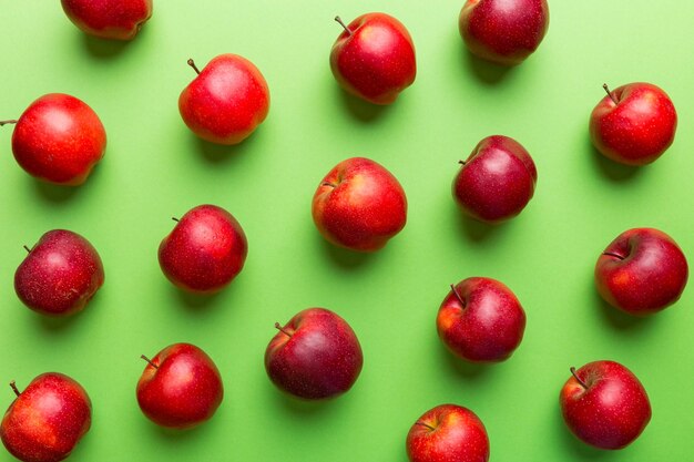 Muchas manzanas rojas sobre fondo de color, vista superior. Patrón de otoño con manzana fresca por encima de la vista.