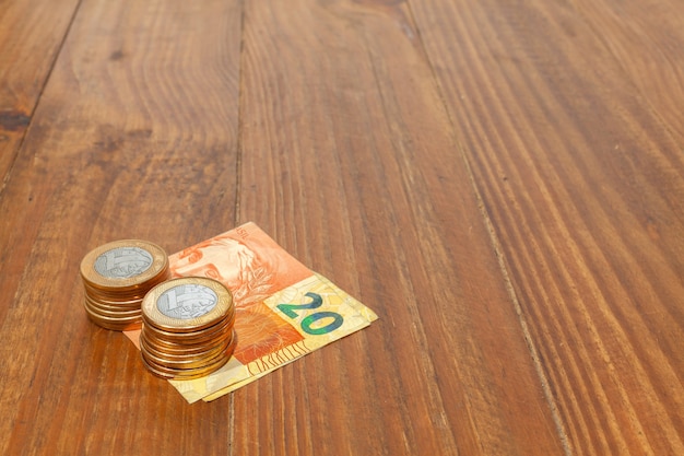 Foto muchas monedas brasileñas y billetes de banco en una mesa de madera