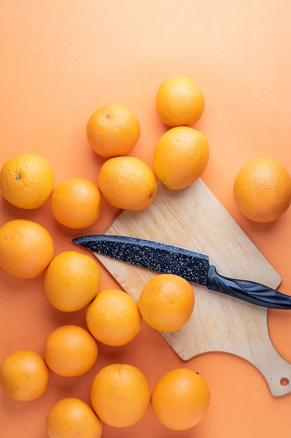 Muchas naranjas y cuchillo en la mesa de la cocina