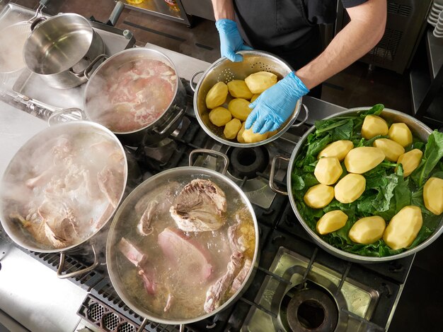 Muchas ollas de cocina hirviendo con estofado, chef cocinando y sin caras mostradas