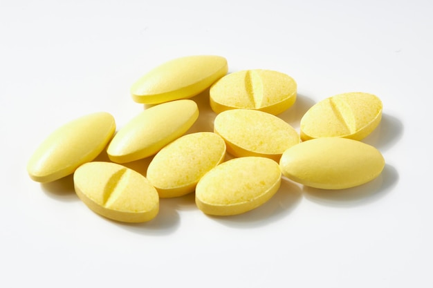 Muchas pastillas amarillas de forma ovalada aisladas en un fondo blanco