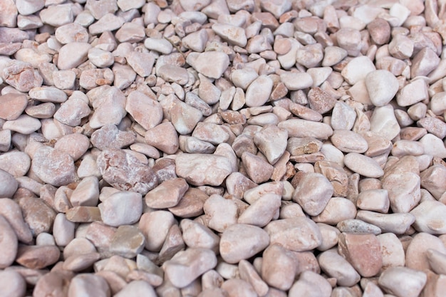 Muchas pequeñas piedras decorativas pulidas utilizadas en el diseño de paisajes con tinte de color rosa.