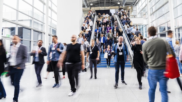 Muchas personas y personas en escaleras mecánicas en una feria comercial