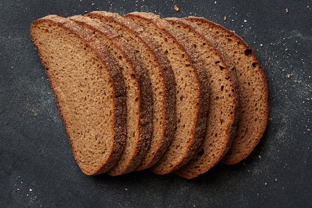 Muchas rebanadas de pan delicioso y fresco representadas una tras otra aisladas sobre fondo negro. Rebanadas de pan de grano. Concepto de pan.