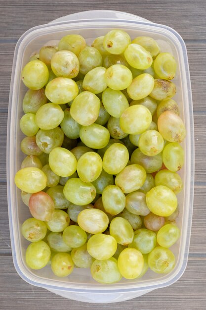 Muchas uvas verdes en una caja de plástico.