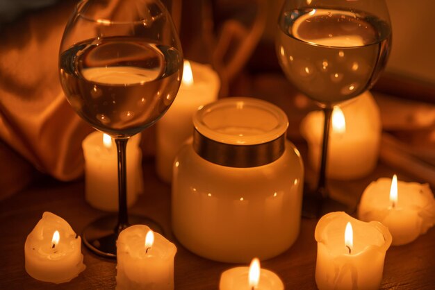 Muchas velas encendidas en la oscuridad y dos vasos de vino blanco cita romántica por la noche