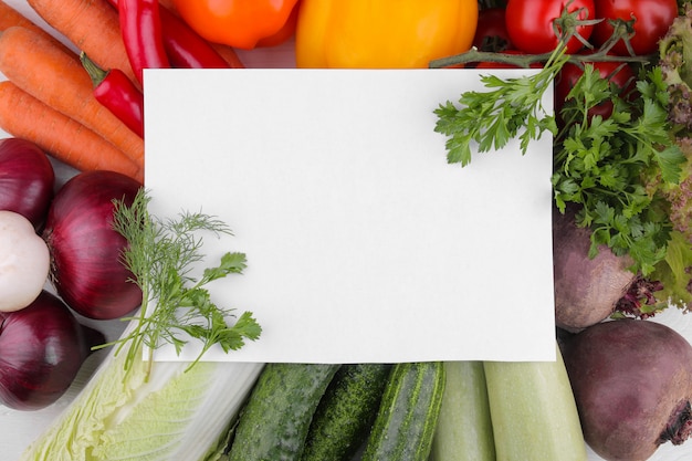 Muchas verduras diferentes con papel en blanco.