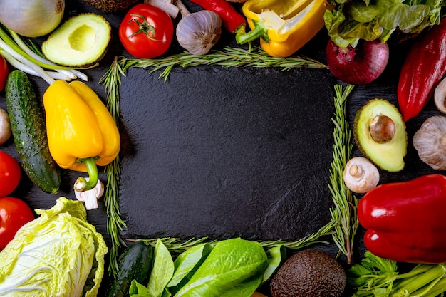 Muchas verduras frescas diferentes sobre un fondo negro con espacio libre para el texto.