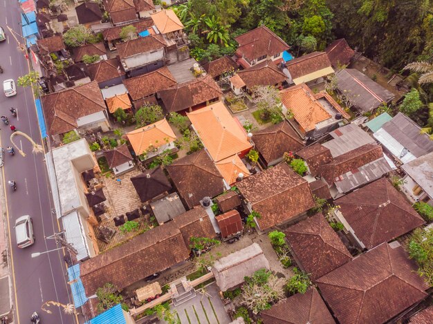 Foto muchas villas con techos de tejas marrón-naranja entre árboles tropicales en el fondo del cielo en ubud en bali el sol está brillando sobre ellos foto horizontal aérea
