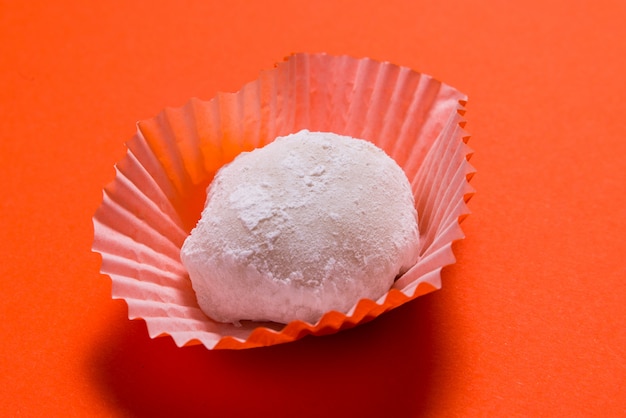 Mucho postre de mochi en vasos de papel sobre mesa rosa