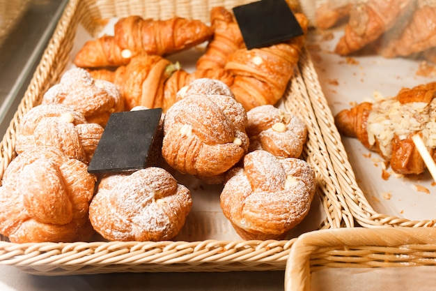 Muchos bollos y cruasanes en un estante de una panadería