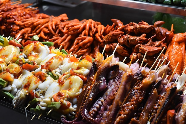 Muchos calamares crudos en brochetas y mariscos en el mercado nocturno vietnamita en Da Lat