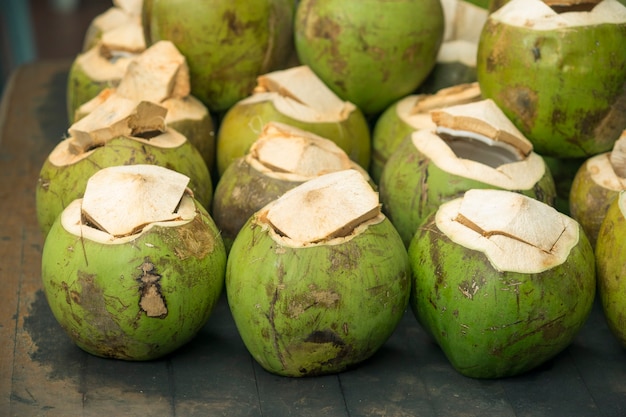 Muchos cocos verdes en mesa vintage con foco en la primera fila