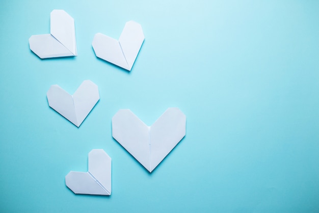 Foto muchos corazones de origami blanco sobre fondo azul. tarjeta de san valentín sobre fondo azul.