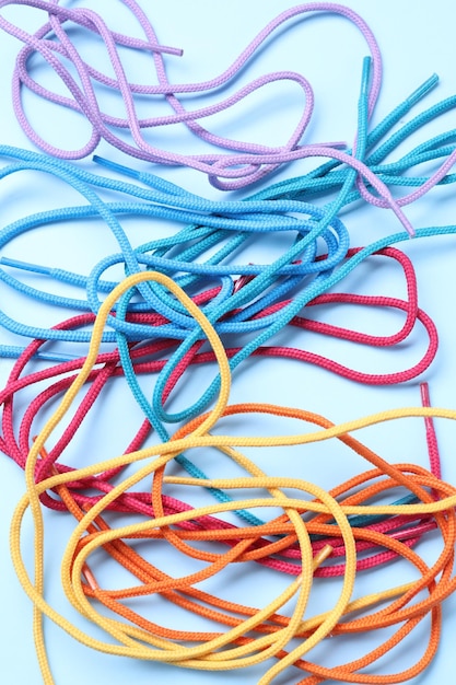 Muchos cordones de zapatos coloridos en fondo azul claro vista superior