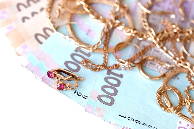 Muchos costosos anillos de joyería de oro aretes y collares con una gran cantidad de billetes de dinero ucraniano Concepto de tienda de empeño o joyería Comercio de joyas