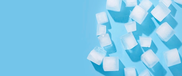 Muchos cubos de hielo grandes sobre un fondo azul Vista superior plano Lay Banner