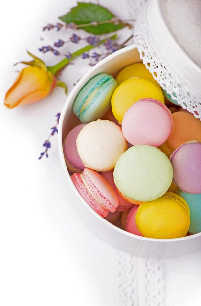 Muchos deliciosos macarons coloridos en caja sobre fondo blanco.