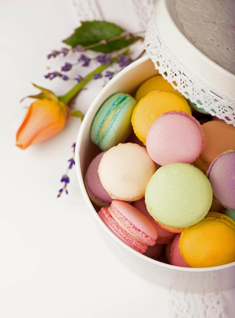 Muchos deliciosos macarons coloridos en caja sobre fondo blanco.