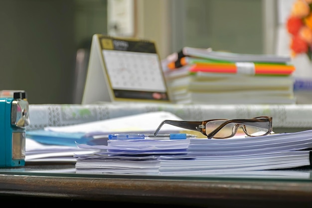 Foto muchos documentos se colocan en el escritorio. los documentos deben verificarse y corregirse usando la habilidad. se colocan un bolígrafo y gafas protectoras.
