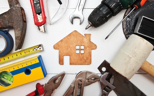 Muchos equipos de reparación diferentes en la mesa de madera y una casita de madera entre ellos