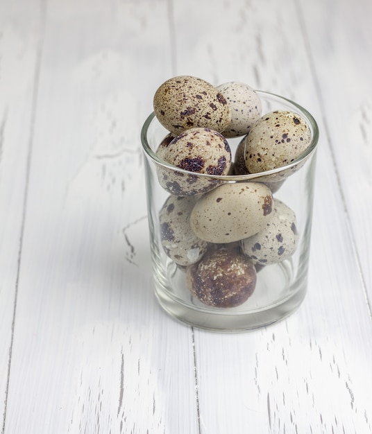 Muchos huevos de codorniz manchados en el vaso sobre la mesa de madera