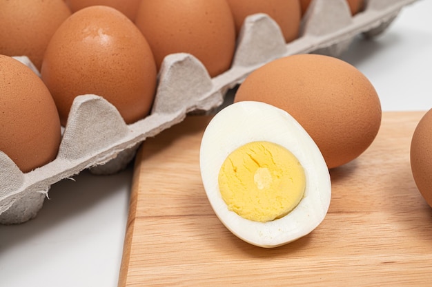 Muchos huevos y huevos cocidos medio cortados en una tabla de cortar de madera