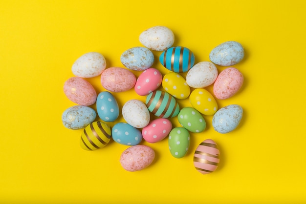 Muchos huevos de Pascua coloridos sobre fondo amarillo brillante. Huevos festivos multicolores