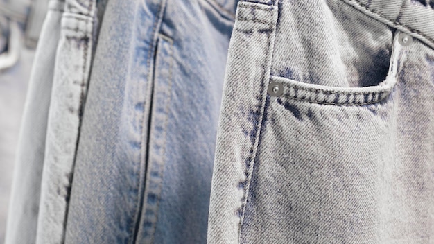 Muchos jeans colgados en arack Fila de pantalones vaqueros colgados en el armario concepto de compra venta compras y moda jeans