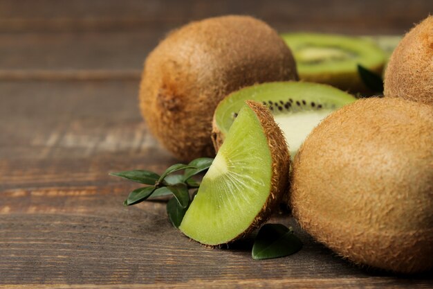 Muchos kiwis maduros deliciosos y kiwi en un corte sobre una mesa de madera marrón. de cerca.