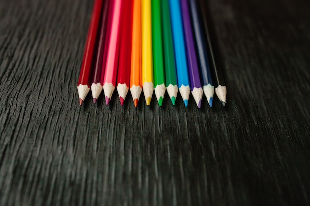 Muchos lápices de colores sobre un fondo negro. Nuevos lapices
