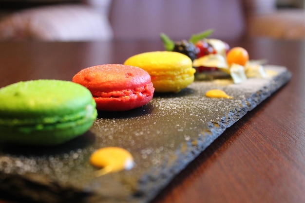 Muchos macarons de colores con crema en la placa blanca.