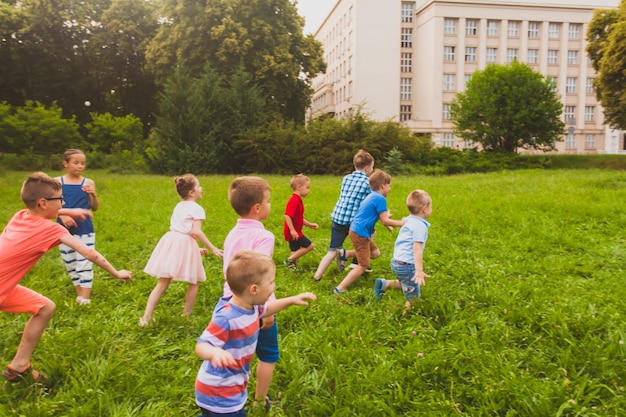 Muchos niños de todas las edades corren por el verde césped del parque.