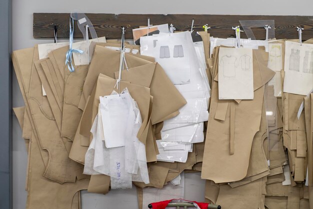 Foto muchos patrones de papel para coser ropa cuelgan en la pared en la fábrica de confección