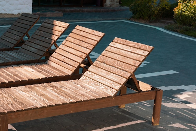 Muchos rayos de sol de madera se encuentran al aire libre Libro abierto en un sillón junto a la piscina Muebles Tumbona Objeto Soleado Cómodo Descanso pacífico Asiento Simplicidad Calma Exótico Resort Luz solar Vacío