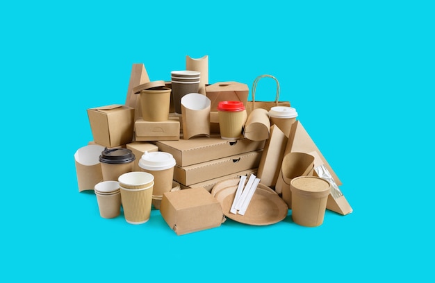 Muchos recipientes de comida para llevar, caja de pizza, tazas de café en soporte y cajas de papel sobre fondo azul agua.