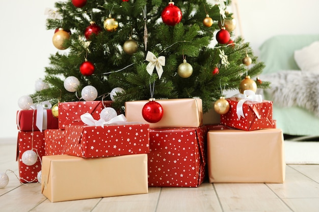 Muchos regalos bajo un árbol de Navidad decorado festivamente en un interior luminoso