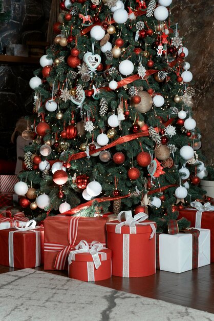 Muchos regalos debajo del árbol de Navidad Diseño interior festivo de año nuevo Cajas de regalo rojas y blancas debajo del árbol de Navidad